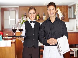 Portrait von einem Kellner und einer Kellnerin mit Wein im Restaurant